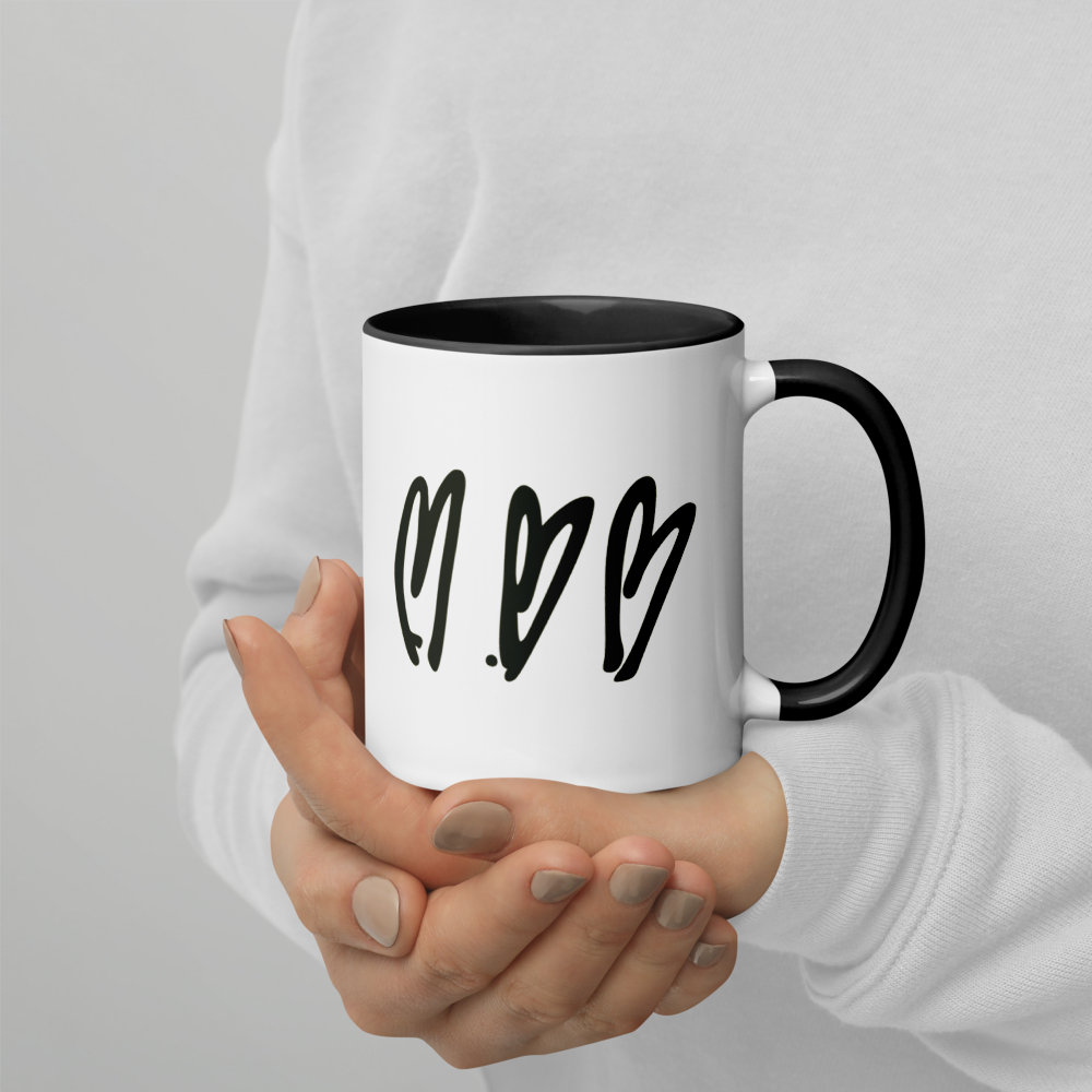 White mug with black interior and handle held by a person against a light gray background