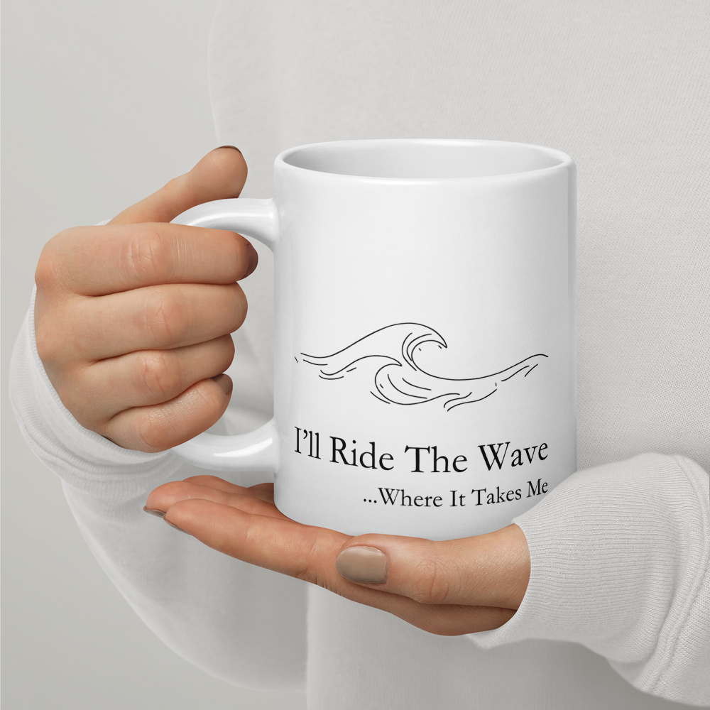 White mug with wave design and text held by a person against a light gray background